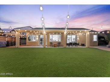 Expansive backyard with lush lawn, covered patio, and charming string lights, perfect for outdoor living and entertaining at 3604 E Derringer Way, Gilbert, AZ 85297