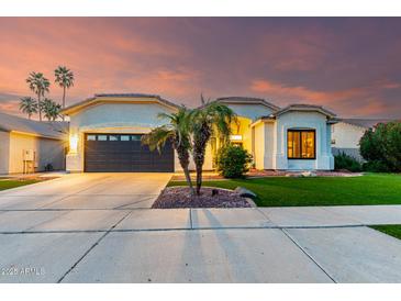 Beautiful one story home with a well-manicured lawn, two palm trees and a two car garage at sunset at 1312 W Bartlett Way, Chandler, AZ 85248