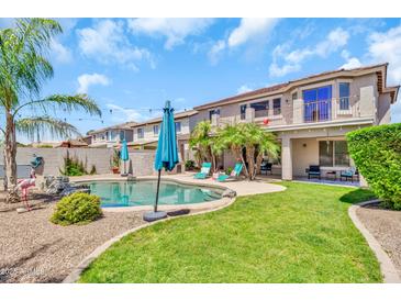Inviting backyard featuring a refreshing pool, lush greenery, and a charming patio area perfect for outdoor entertaining at 21167 E Aspen Valley Dr, Queen Creek, AZ 85142