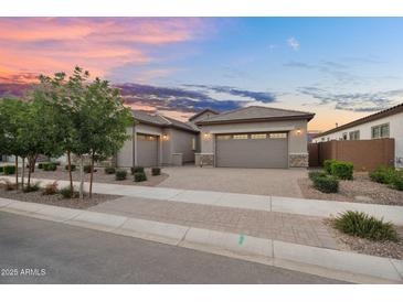 Charming home featuring a three car garage, a brick driveway, and desert landscaping in front at 21934 E Lords Ct, Queen Creek, AZ 85142
