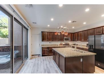 Modern kitchen boasts stainless steel appliances, granite counters, and an island with a sink at 2275 N Heritage St, Buckeye, AZ 85396