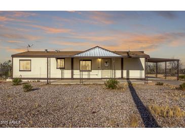 Inviting one-story home featuring a covered front porch, porte-cochere, and a gravel yard for low-maintenance living at 3349 N Ralston Rd, Maricopa, AZ 85139