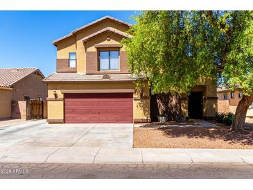 Two-story home featuring a front yard with mature trees and a red two-car garage door at 6320 S 26Th Dr, Phoenix, AZ 85041