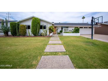 Charming single-story home featuring desert landscaping, a basketball hoop, and a well-manicured lawn at 6608 E Lewis Ave, Scottsdale, AZ 85257