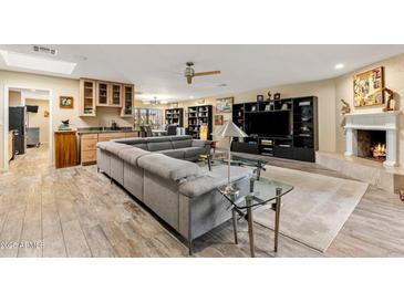 Spacious living room featuring a large sectional sofa, fireplace, and built-in shelving at 7673 N Via De Platina Dr, Scottsdale, AZ 85258