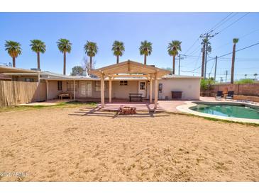 Expansive backyard featuring a refreshing pool, covered patio, and lush palm trees at 809 N Gilbert Ave, Casa Grande, AZ 85122