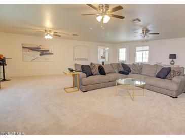 Bright living room featuring a large sectional sofa and multiple ceiling fans for added comfort at 809 N Gilbert Ave, Casa Grande, AZ 85122