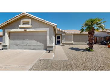 Charming single-story home featuring a two-car garage, desert landscaping, and a cozy front porch at 884 W 15Th Ave, Apache Junction, AZ 85120