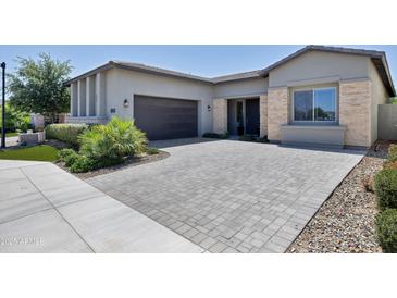 Charming single-story home featuring desert landscaping, a dark garage door, and a spacious paved driveway at 17183 W San Marcos St, Surprise, AZ 85388