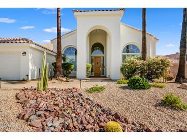 Inviting home featuring a beautiful front yard, mature palms, and an arched entry at 11993 E Mission Ln, Scottsdale, AZ 85259