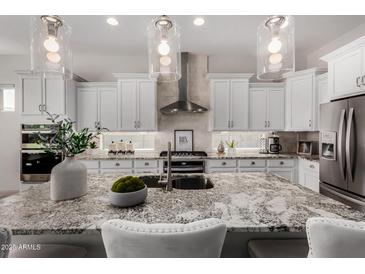 A close-up of the kitchen island featuring granite countertop, stainless appliances, and pendant lighting at 16373 W Beautiful Ln, Goodyear, AZ 85338