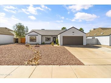 Inviting single-story home with desert landscaping, a gray roof, and a two-car garage at 19039 N 47Th Ave, Glendale, AZ 85308
