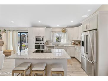 Bright kitchen featuring white cabinets, stainless appliances, granite counters and island with seating at 19039 N 47Th Ave, Glendale, AZ 85308