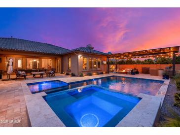 Inviting backyard pool and spa with outdoor seating, a fire pit, and a pergola at dusk at 5428 E Windstone Trl, Cave Creek, AZ 85331