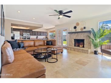 Spacious living room with a stone fireplace and light-filled views of the exterior at 6819 E Sheena Dr, Scottsdale, AZ 85254
