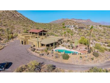 Expansive desert home features a sparkling pool, attached garage, and a unique architectural design amidst a stunning natural landscape at 8752 E Range Rider Trl, Mesa, AZ 85207