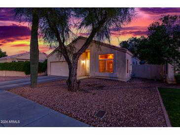 Charming single-story home with desert landscaping, and a warm inviting glow from the large front window at 10735 W Bermuda Dr, Avondale, AZ 85392