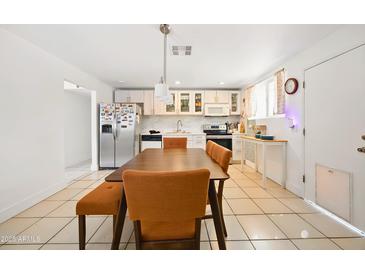 Bright kitchen featuring white cabinets, stainless steel appliances, and dining area with seating at 3701 E Karen Dr, Phoenix, AZ 85032