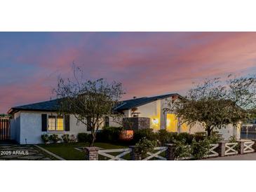 Charming home featuring a cozy brick fireplace, green landscaping, and a brick and white wood fence at 4021 E Glenrosa Ave, Phoenix, AZ 85018