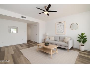 Bright living room features modern ceiling fan, neutral paint and decor, plus wood-look flooring at 7801 N 44Th Dr # 1003, Glendale, AZ 85301