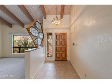 Inviting foyer with a wooden front door, unique art piece, and wood-beamed ceilings offering a warm welcome at 9008 N 83Rd St, Scottsdale, AZ 85258