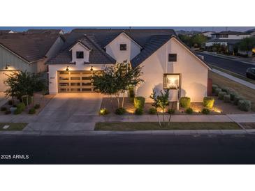 Charming home featuring modern architectural design, a two-car garage, manicured landscaping, and inviting outdoor lighting at 10127 E Tillman Ave, Mesa, AZ 85212