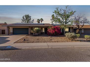 Charming single-story home boasts solar panels, a lush bougainvillea, and a two-car garage at 116 E Helena Dr, Phoenix, AZ 85022