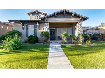 Charming single-story home featuring stone accents, a well-manicured lawn, and a welcoming front porch at 4565 N Point Ridge Rd, Buckeye, AZ 85396