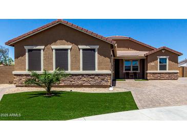 Inviting single-story home featuring a landscaped front yard with desert accents and a brick paved driveway at 15740 W Washington St, Goodyear, AZ 85338