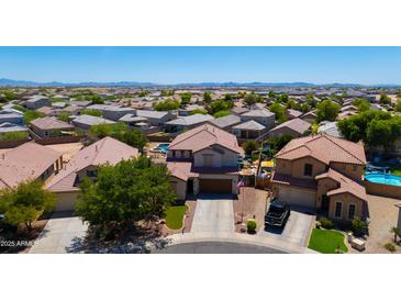 Expansive aerial view of a suburban home featuring a pool, lush landscaping, and a tile roof at 19324 N Del Mar Ave, Maricopa, AZ 85138