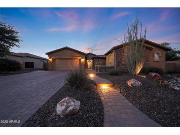 Charming home exterior with a paved walkway, desert landscaping, and warm lighting at dusk at 19334 W Pasadena Ave, Litchfield Park, AZ 85340