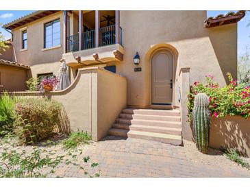 Inviting front entrance with a charming arched doorway, desert landscaping, and a private balcony above at 20704 N 90Th Pl # 1015, Scottsdale, AZ 85255