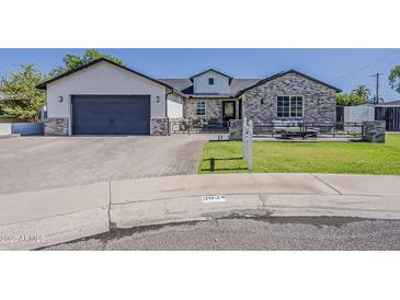 Charming home featuring a brick and stucco facade, complemented by a well-manicured lawn and a stylish driveway at 3834 E Clarendon Ave, Phoenix, AZ 85018
