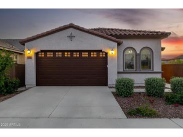 Inviting front exterior featuring a tile roof, arched windows, two-car garage, and beautifully landscaped yard at 4352 N 91St Gln, Phoenix, AZ 85037