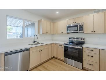 Bright kitchen featuring stainless steel appliances, light wood cabinets and white countertops at 6601 N 46Th Ln, Glendale, AZ 85301