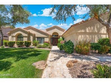 Charming single-story home featuring a lush green lawn and a stone walkway leading to the front door at 7734 E Monica Dr, Scottsdale, AZ 85255