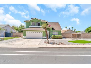 Charming two-story green home with a well-manicured front yard and white two-car garage at 8871 W Maryland Ave, Glendale, AZ 85305