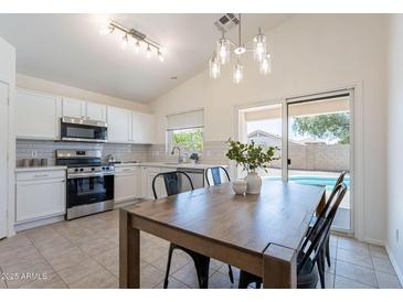 Eat-in kitchen features stainless steel appliances, white cabinetry, and a view of the pool at 11805 W Sunnyside Dr, El Mirage, AZ 85335
