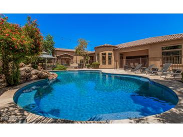 Inviting pool with a rock feature and lounge chairs, all set against a backdrop of manicured landscaping at 24348 S 201St Ct, Queen Creek, AZ 85142