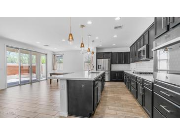 Bright, open kitchen with modern appliances, island with pendant lighting, and sliding doors to the patio at 31653 N 24Th Dr, Phoenix, AZ 85085