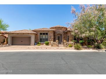 Charming stone home featuring a tile roof, two-car garage, and beautiful landscaping at 7134 E Sandia St, Mesa, AZ 85207
