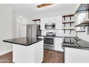 Bright kitchen featuring stainless steel appliances, a center island with granite countertop, and open wooden shelving at 1350 S Greenfield Rd # 1166, Mesa, AZ 85206