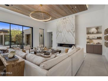 Bright living room featuring a fireplace with marble surround and wood plank ceiling with modern, round light fixture at 24863 N 103Rd Way, Scottsdale, AZ 85255