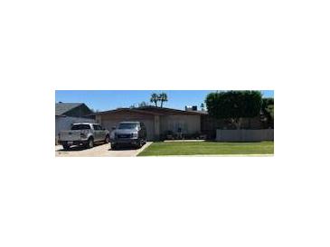 Well-maintained single-story home featuring a lush green lawn and a driveway with two parked vehicles at 2501 E Pebble Beach Dr, Tempe, AZ 85282