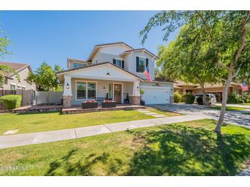 Inviting two-story home featuring a green lawn, charming front porch, and a lovely gray and white color scheme at 3931 E Weather Vane Rd, Gilbert, AZ 85296