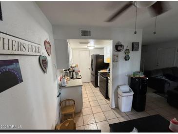 Galley style kitchen features tile floors, white cabinets and a full appliance package in a cozy layout at 4002 W Palomino Rd, Phoenix, AZ 85019