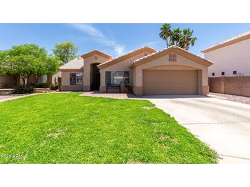 Charming single-story home featuring a lush green lawn and a two-car garage at 423 W Century Ct, Gilbert, AZ 85233
