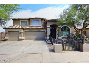 Charming two-story home features a tile roof, arched entryway, three-car garage and gated courtyard at 4530 E White Feather Ln, Cave Creek, AZ 85331