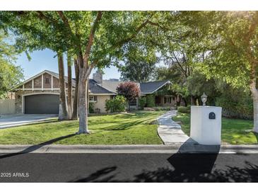 Charming single story home with mature trees, lush lawn, and unique stone and brick accents on a sunny day at 5112 N 41St St, Phoenix, AZ 85018
