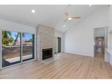 Bright living room featuring vaulted ceilings, cozy fireplace, and sliding glass doors at 7810 E Via Camello -- # 72, Scottsdale, AZ 85258